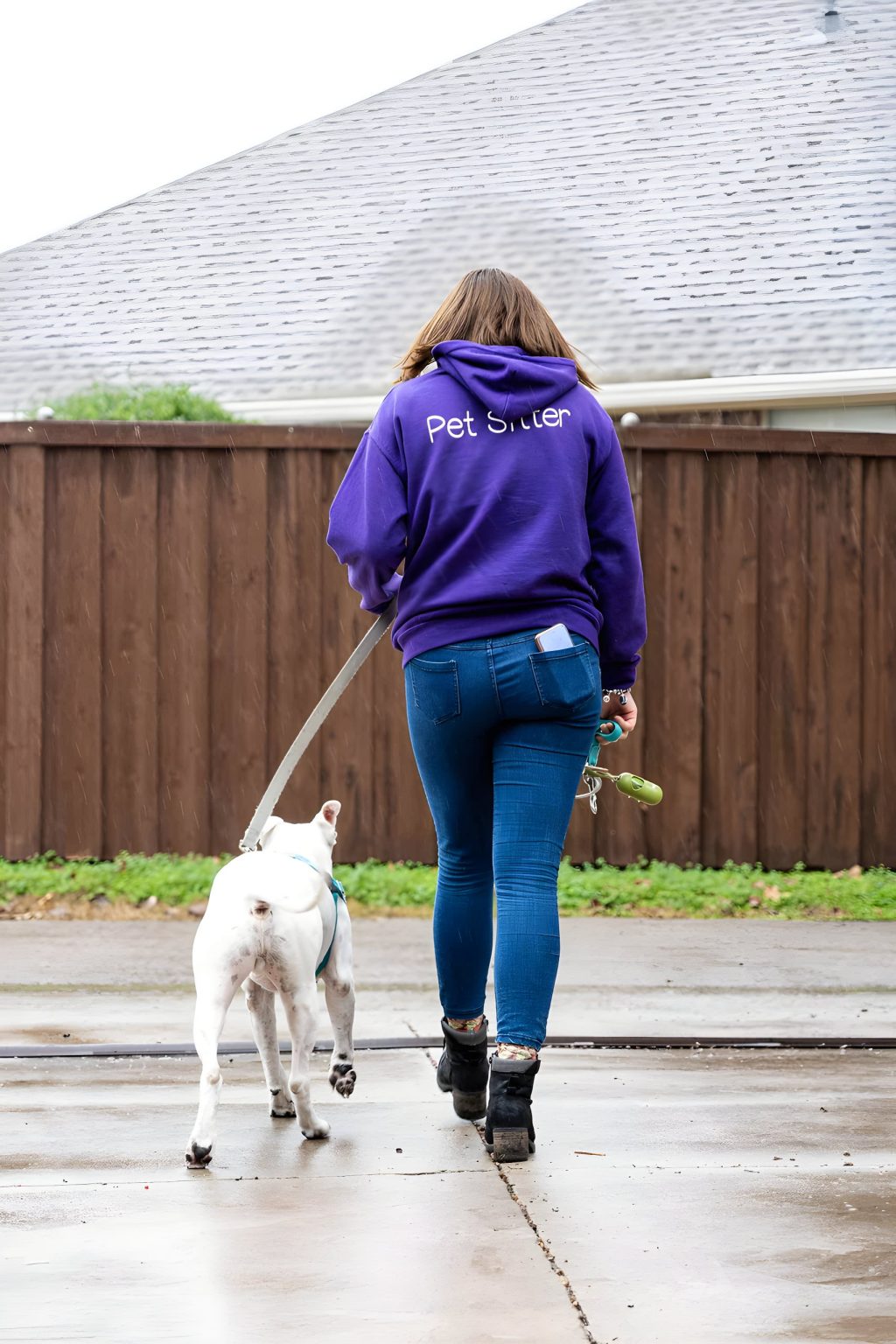 A Pet Companion walking a leashed white dog down a residential street
